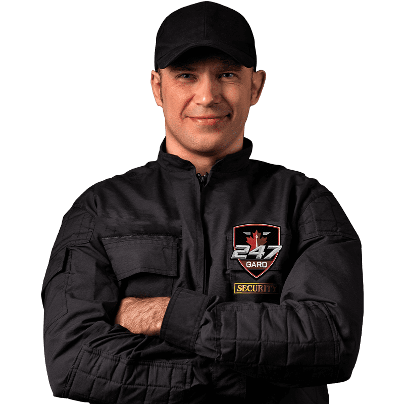 A middle-aged male security guard from 247 Gard Security with short dark hair, wearing a black jacket and hat, standing confidently in front of a black background with a 247 Gard Security badge on his jacket.